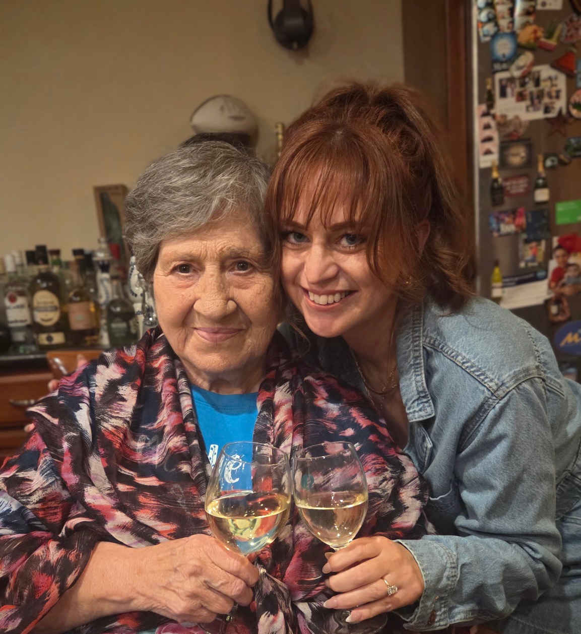 Grandma and Ashlee cheek to cheek, toasting with white wine